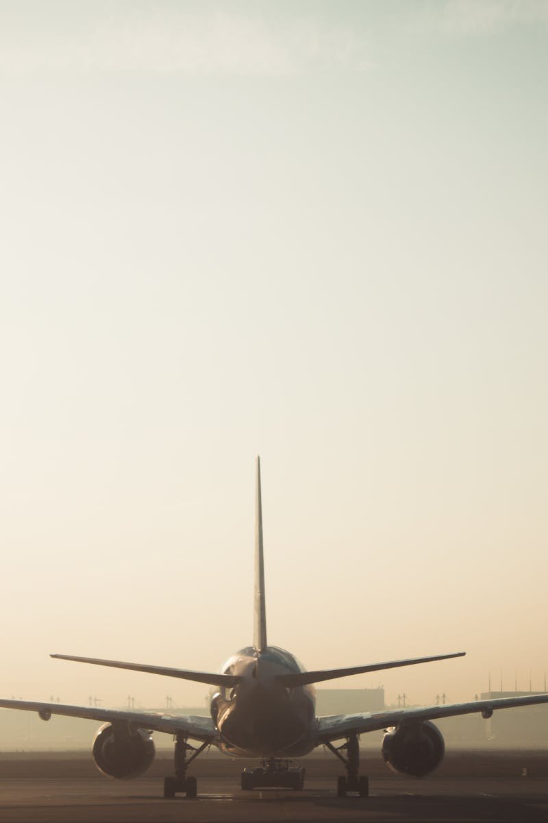 A misty morning scene of a plane on the runway with a hazy sky background, showcasing air travel ambiance.